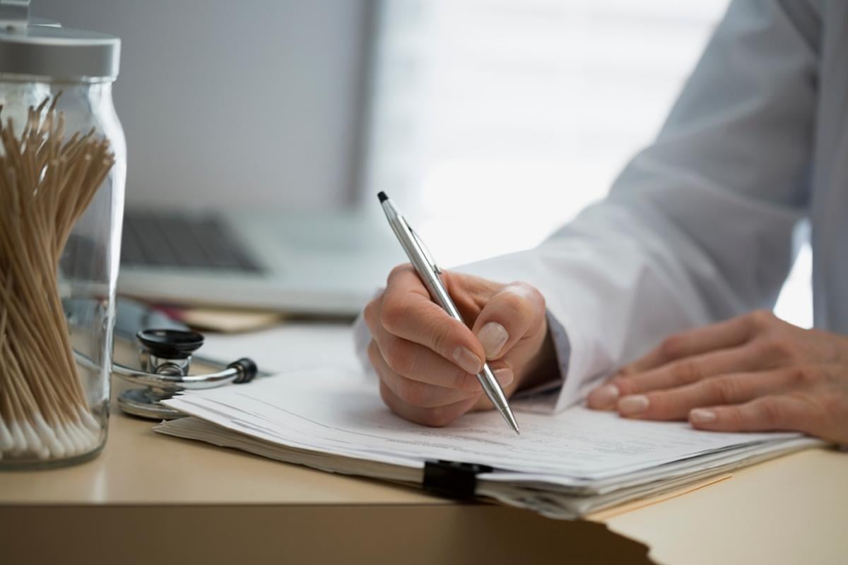 Physician making notes on a pile of papers.